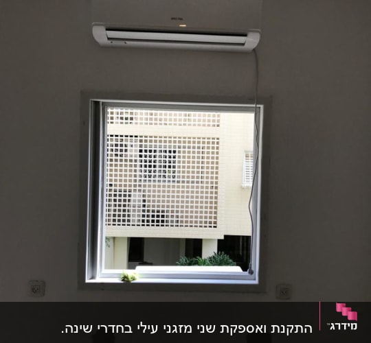 מזגן מותקן מעל חלון עם כבל חשמל תלוי